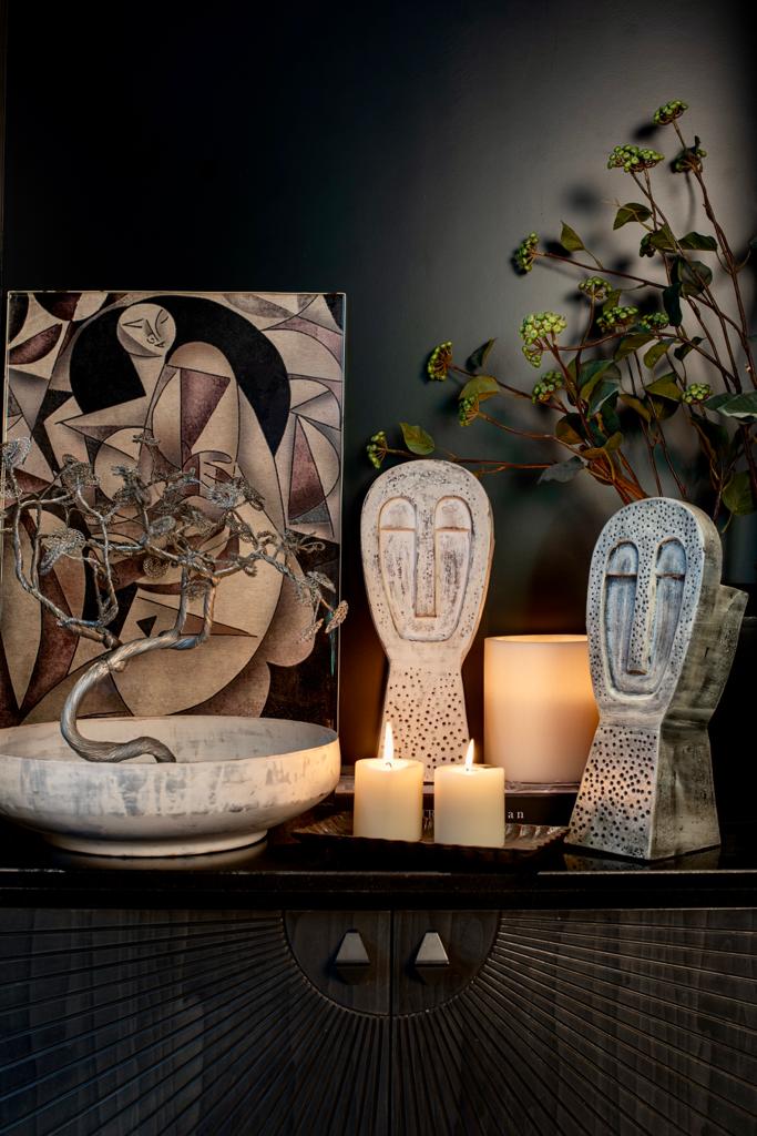 Candles with sculptures and vase with metal art in the background