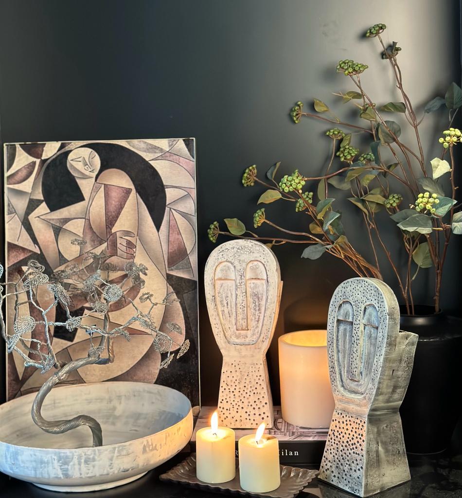 Candles with sculpture and vase with metal art in the back ground 